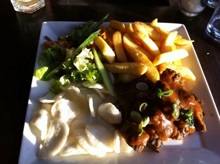 a square white plate with a plate full of food and french fries