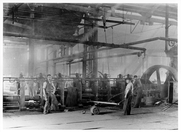 three men standing in front of machines in a factory