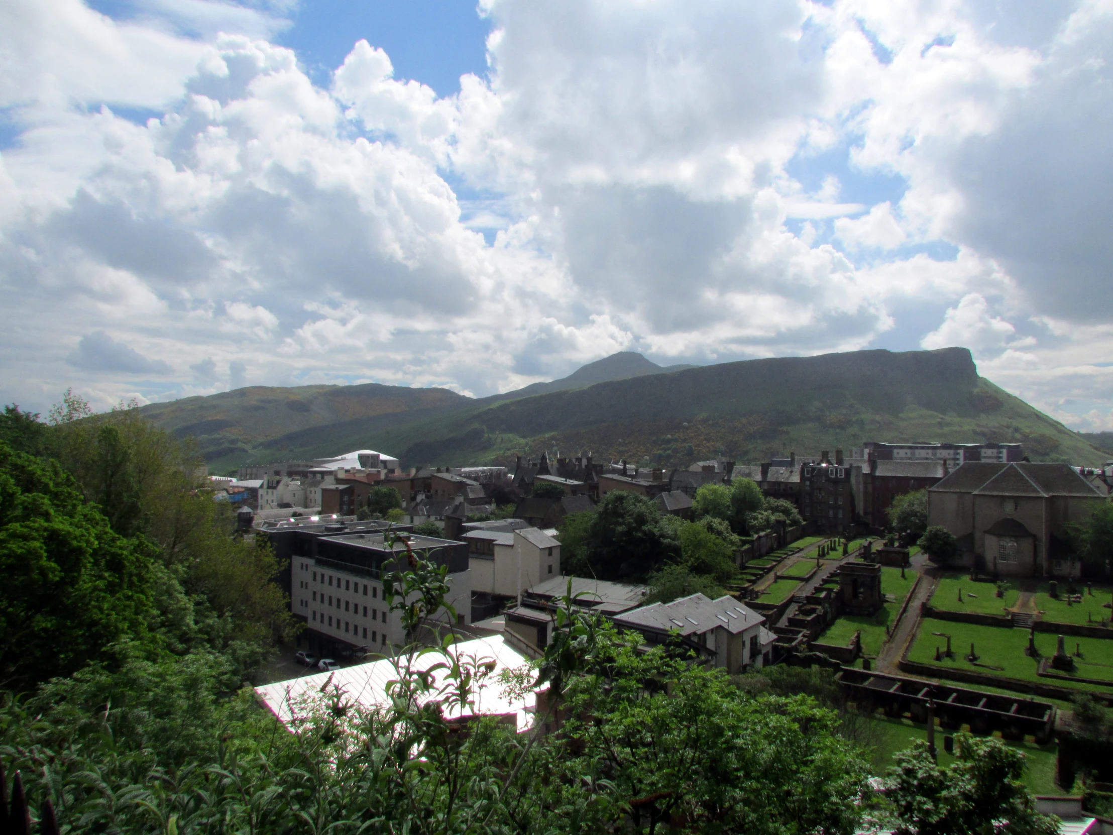 a view of some buildings and mountains with clouds in the sky