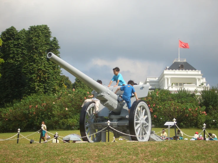 two men working on an iron cannon with a flag in the back
