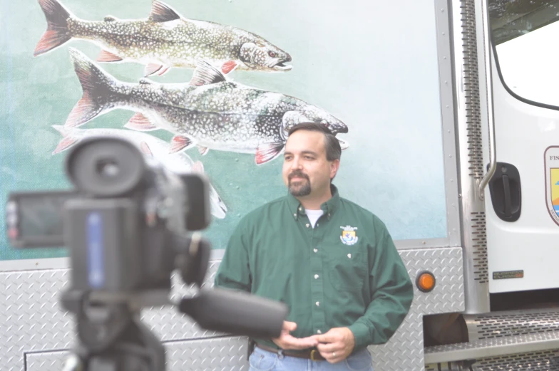 a camera man next to a television truck with fish on it