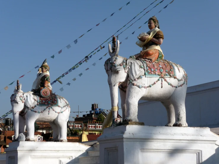 the two statues are depicting elephants in front of buildings