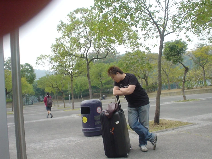 a man carrying a luggage bag near some trees