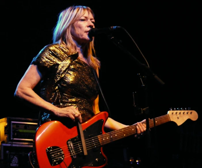 the woman is playing a red guitar at the stage