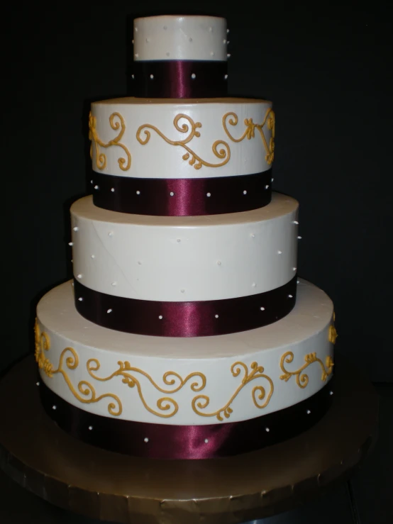 a three layer cake with gold and burgundy decorations