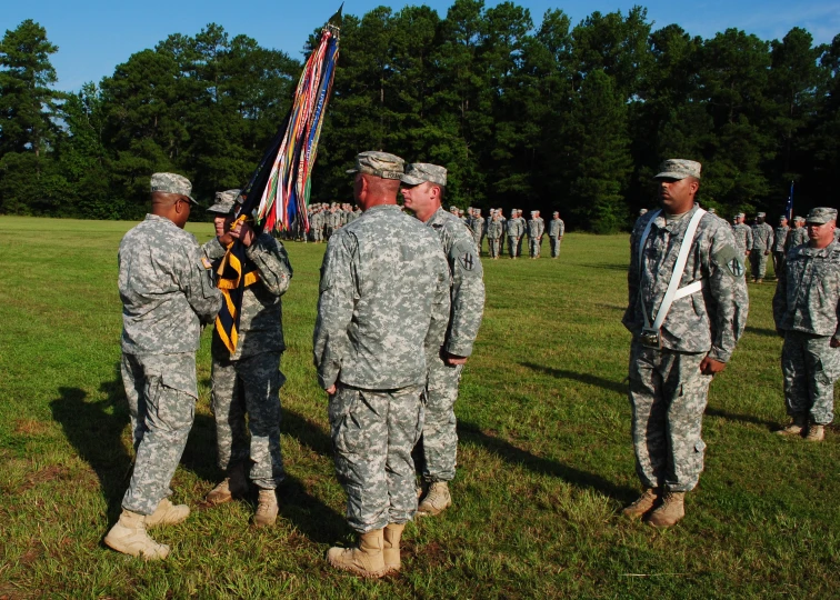 soldiers gather in a field holding the flag