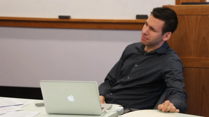 a man sitting at a table working on his laptop