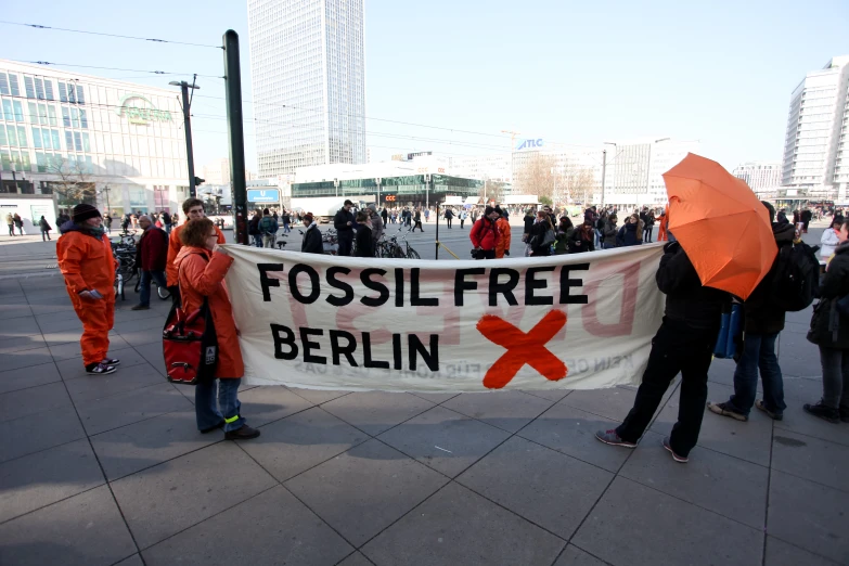 people are holding an orange umbrella and banner