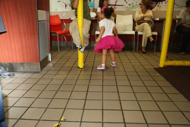 small girl in pink and white dress walking through room