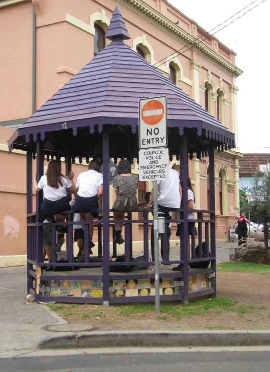 a purple colored roofed wooden gazebo in a small area of concrete