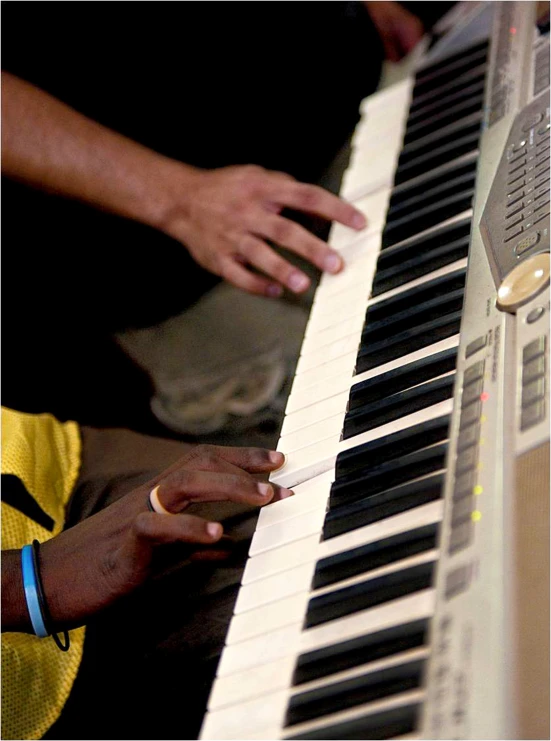 some hands playing the piano while others are around