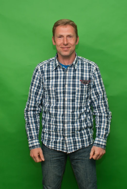 a man stands in front of a green wall