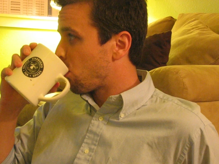 a man in a gray shirt holds up a starbucks mug