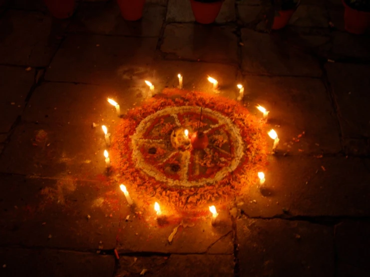 lighted diya with flowers on the floor at night