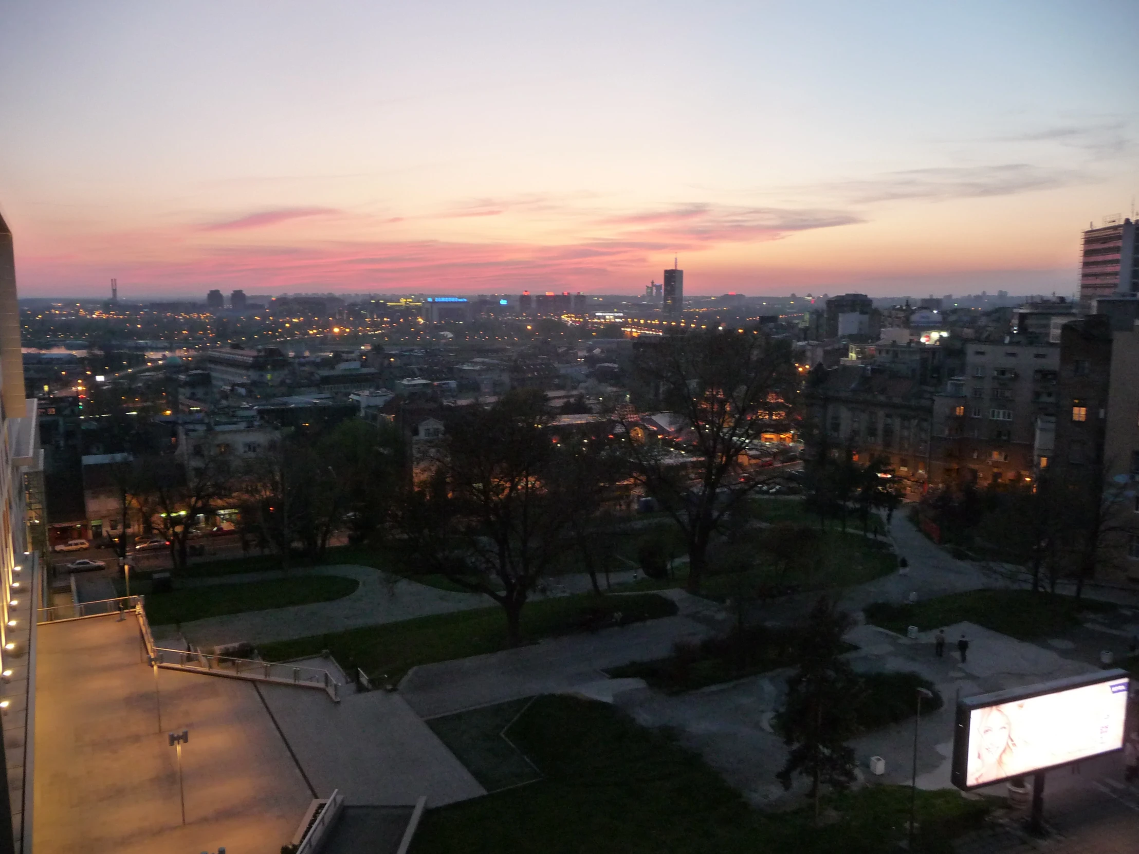 a cityscape view of buildings and an empty park at night