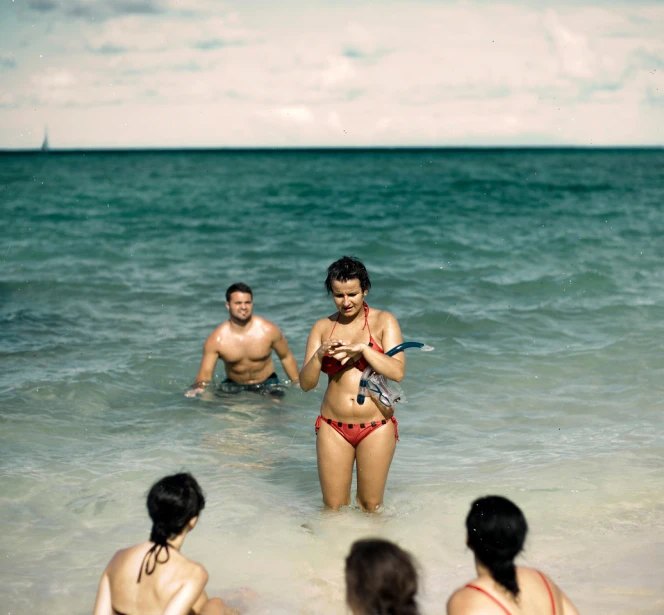 a couple in their swimsuits are holding a device in the water