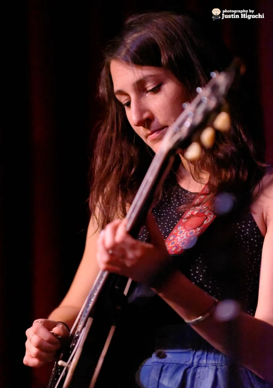 a woman standing with her guitar looking at it