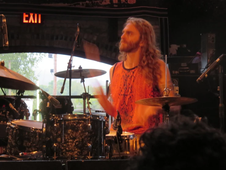 a drummer plays drums while a group of spectators looks on