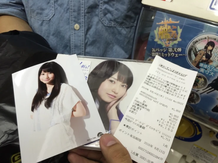 someone holding two japanese pocards over some other papers