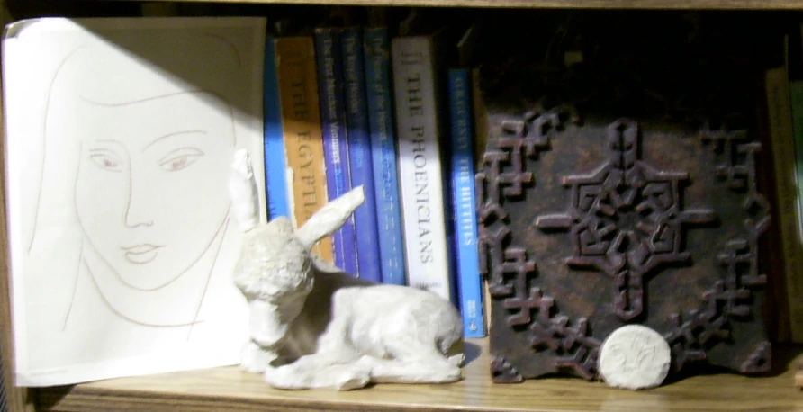 white statue in a wooden book case with bookcase