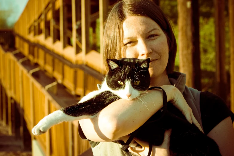 the woman is posing with her cat outside