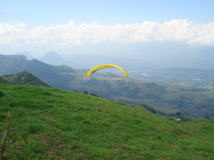 a kite flying over a lush green hillside