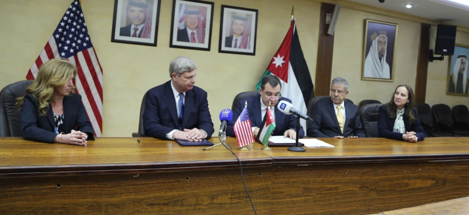 five people are sitting around a large table with microphones