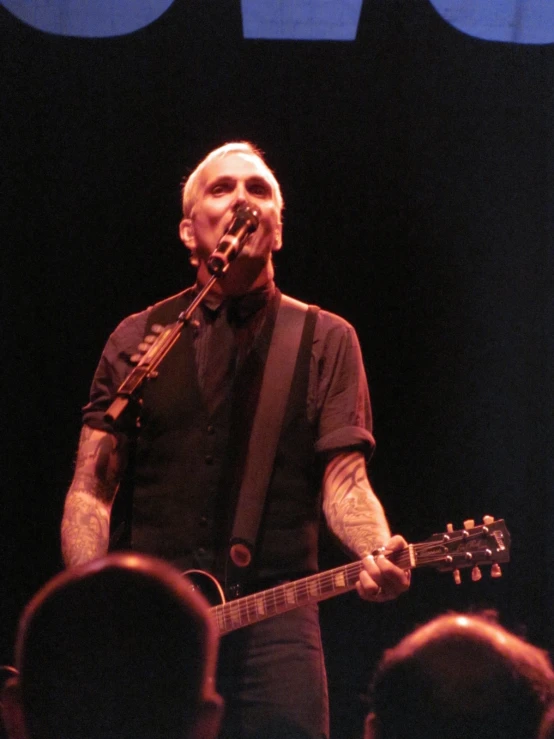 man in black shirt with guitar and microphone