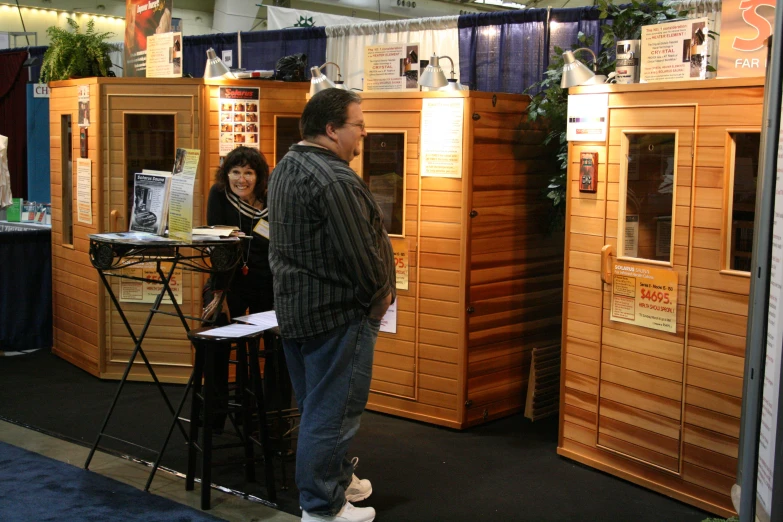 two people talk to each other in front of booths made of wooden crates