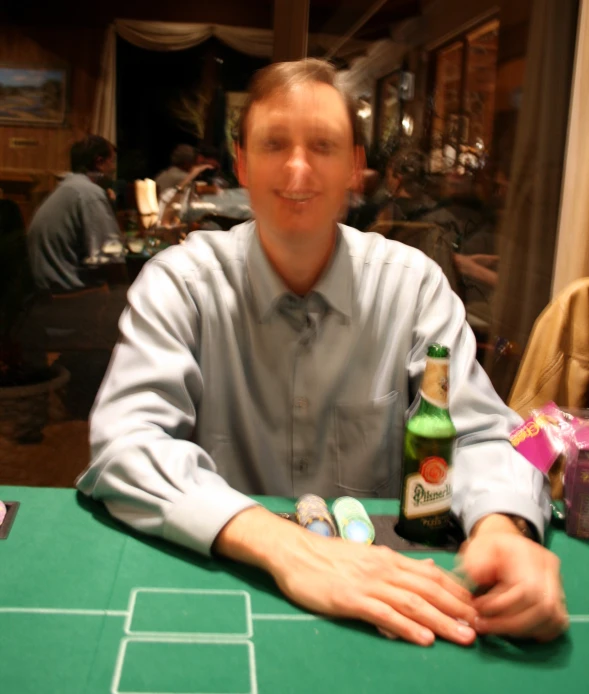 a man in shirt and tie posing at a table with bottle and chips