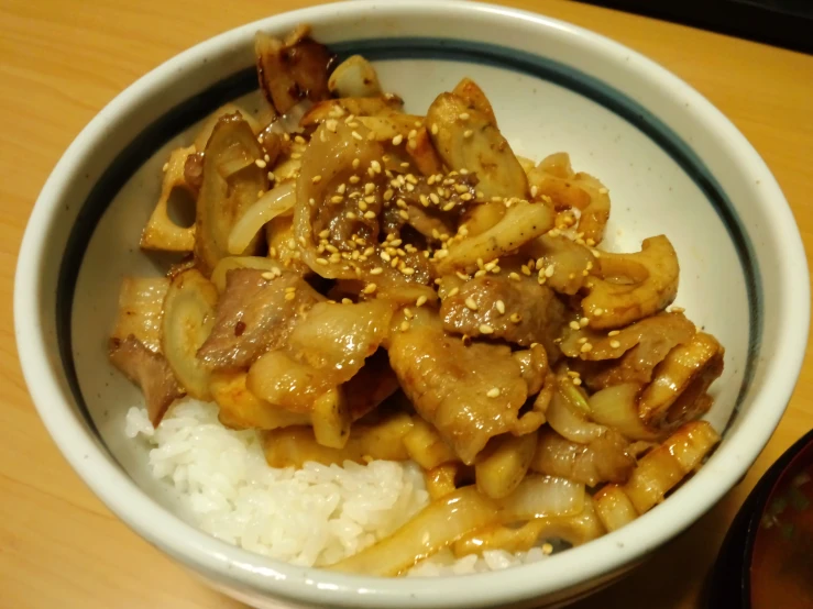 a bowl with rice, meat and nuts on it