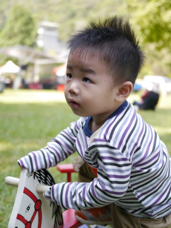 a small boy sitting on top of a red and white toy