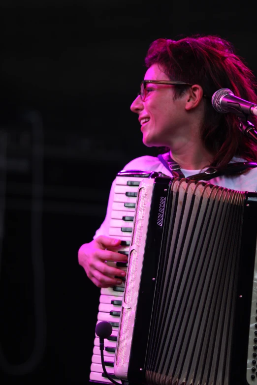 a man holding a microphone, and playing an accordeon