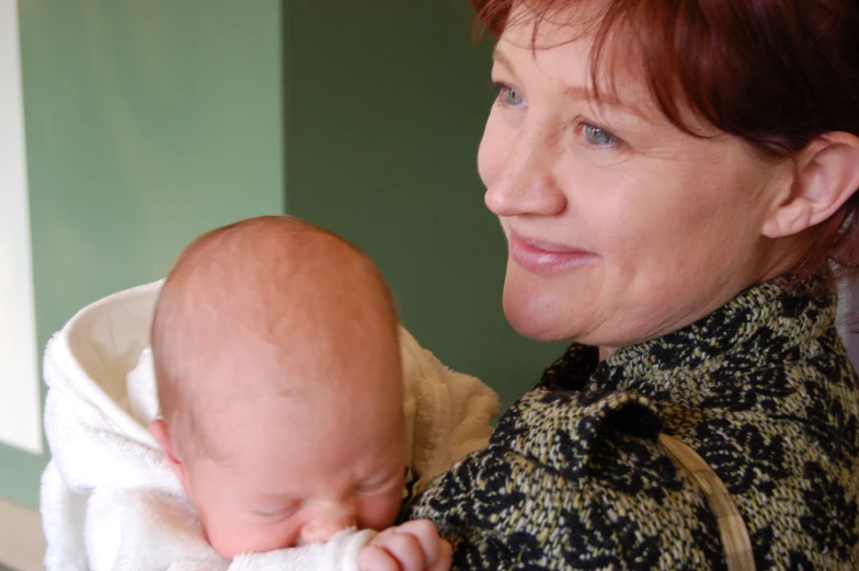 an older woman holding a baby wrapped in a towel