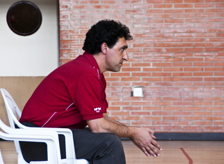 man sitting on chair in an indoor facility with brick wall