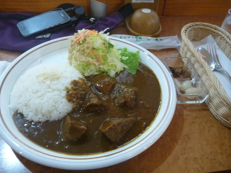 a bowl filled with meat, rice and a piece of lettuce