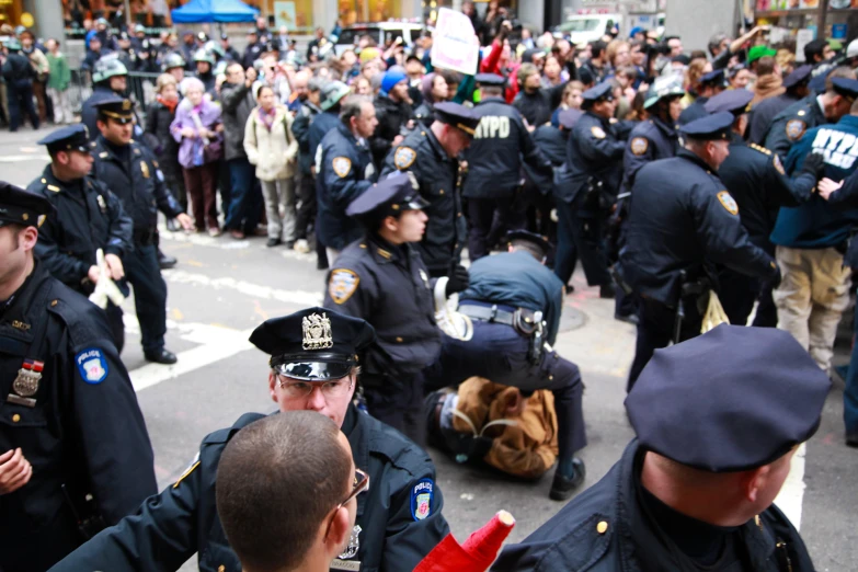 police officers and crowd walking along sidewalk during daytime