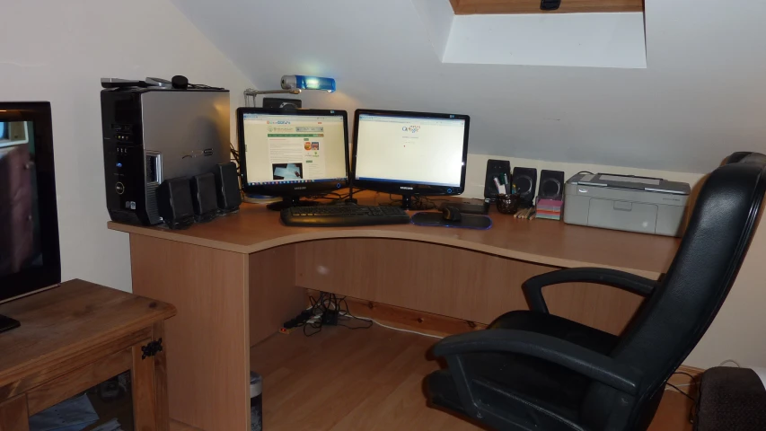 two computer screens sit on a corner desk in front of a computer monitor