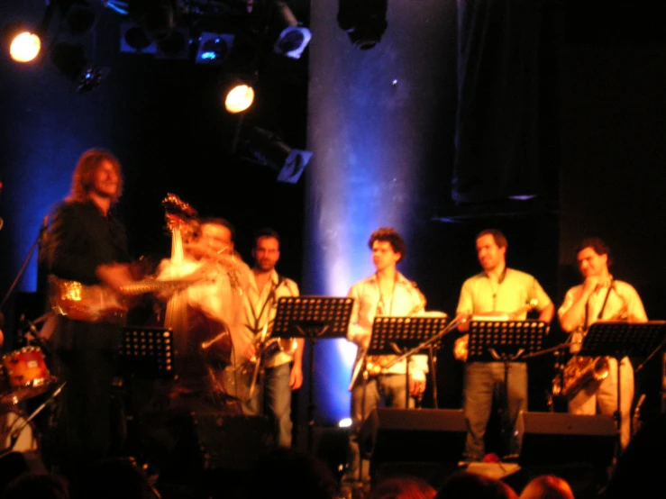 group of musicians performing on stage at indoor concert