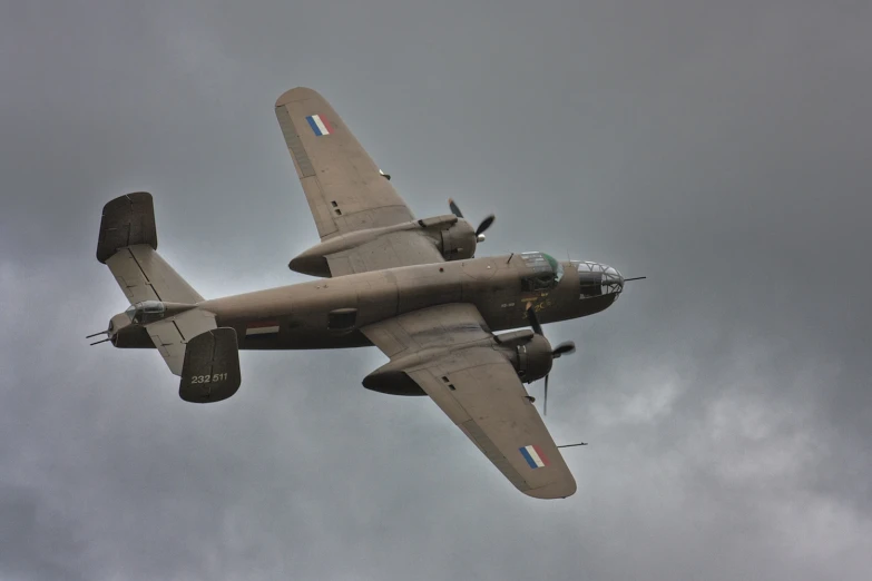 an old world war ii plane flying in the cloudy sky