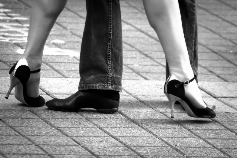 two legs with black and white heels on a brick street