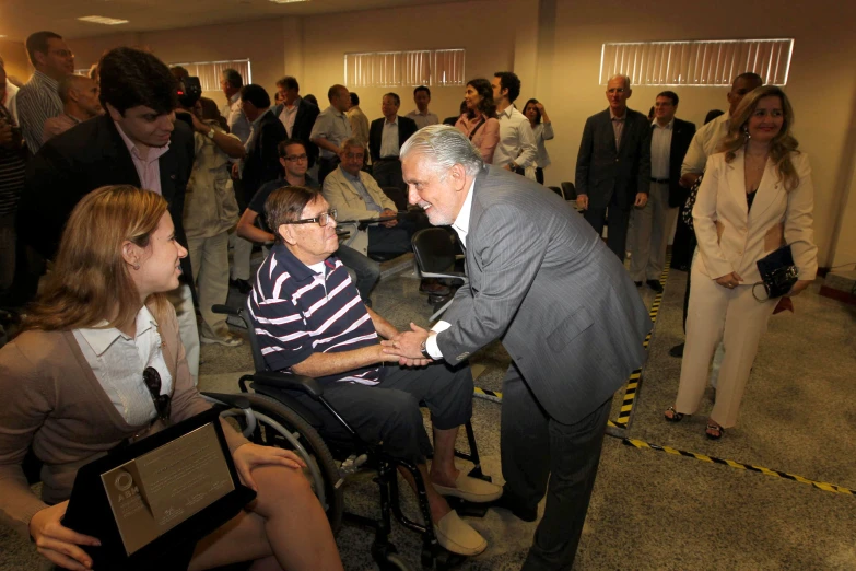 two people shaking hands in front of a crowd of people