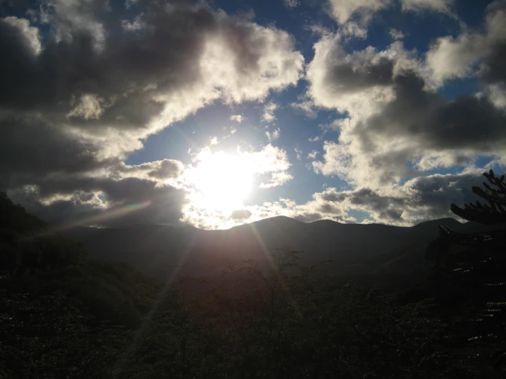 a sun shines brightly over a mountainous valley