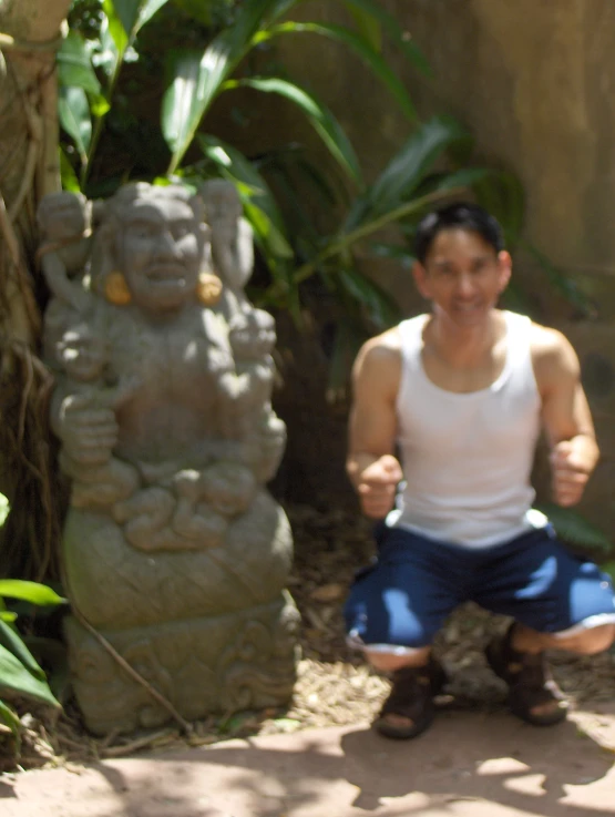 a man is giving thumbs up sitting next to some statues