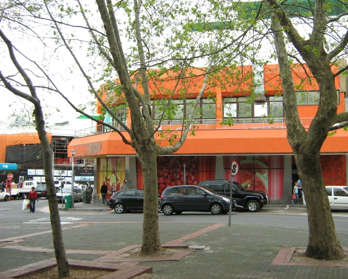 cars and pedestrians are traveling by this colorful building