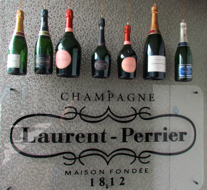 bottles of champagne hanging from a sign for laurent perrie, paris
