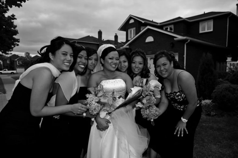 a bunch of pretty women standing next to each other in front of a house