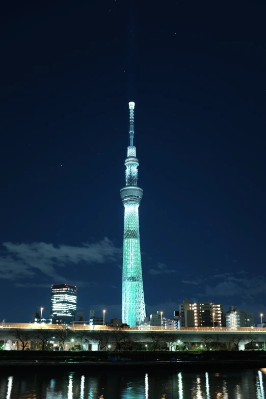 a bright, blue spire with a lighted top is lit up at night