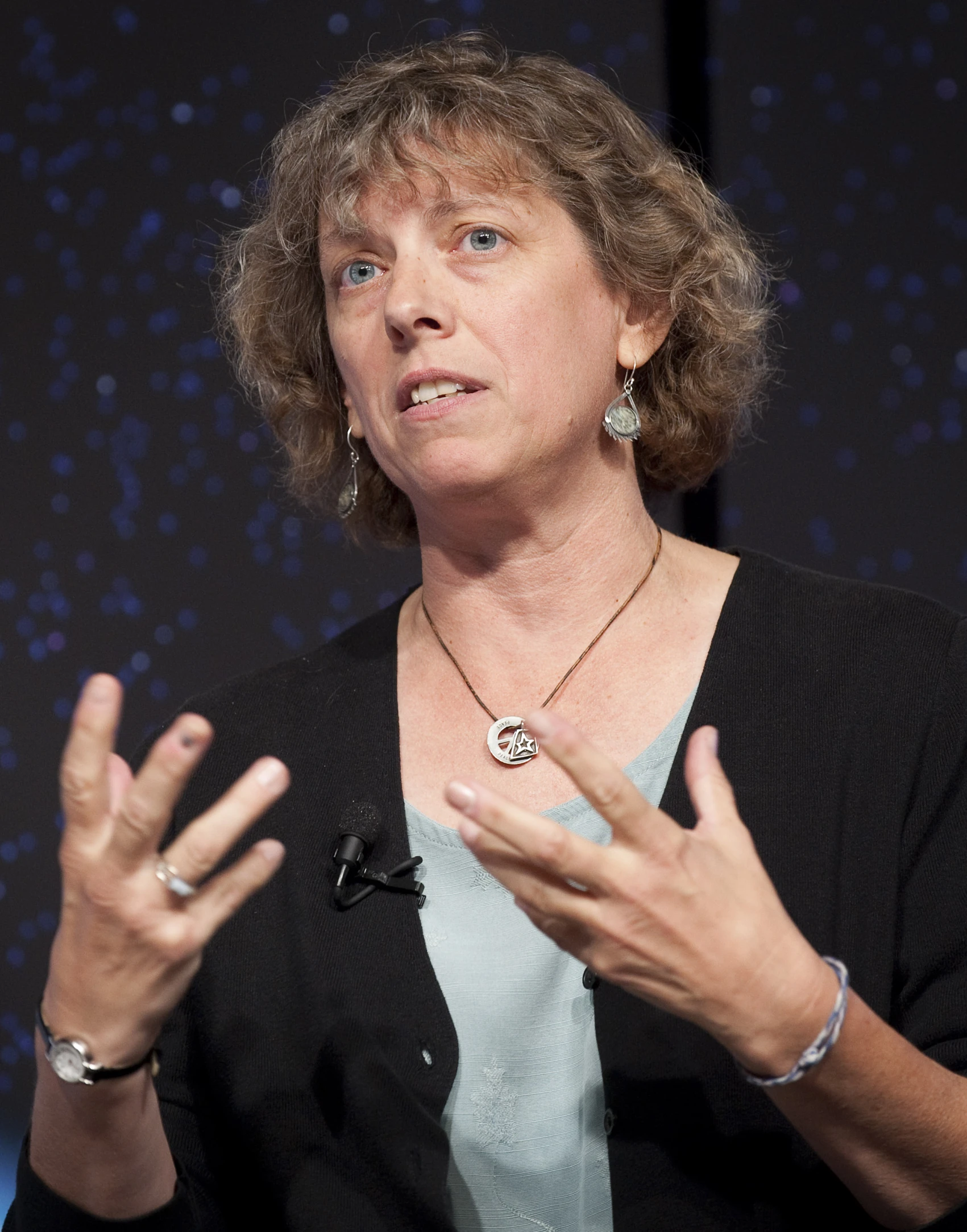 a woman in a black top and necklace on