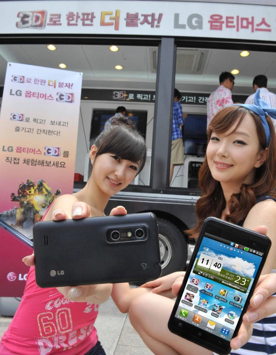 two women posing with their cell phones at an event